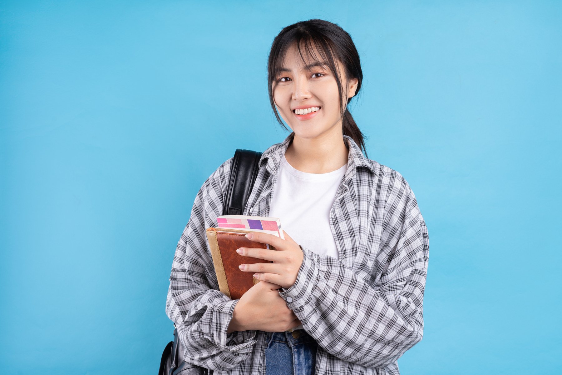 Asian Female Student with Playful Expression on Blue Background