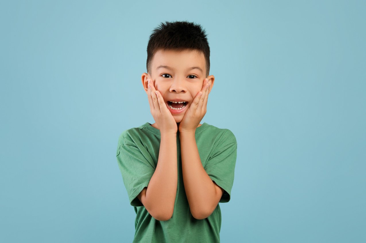 Portrait of Surprised Little Asian Boy Touching Face with Excitement